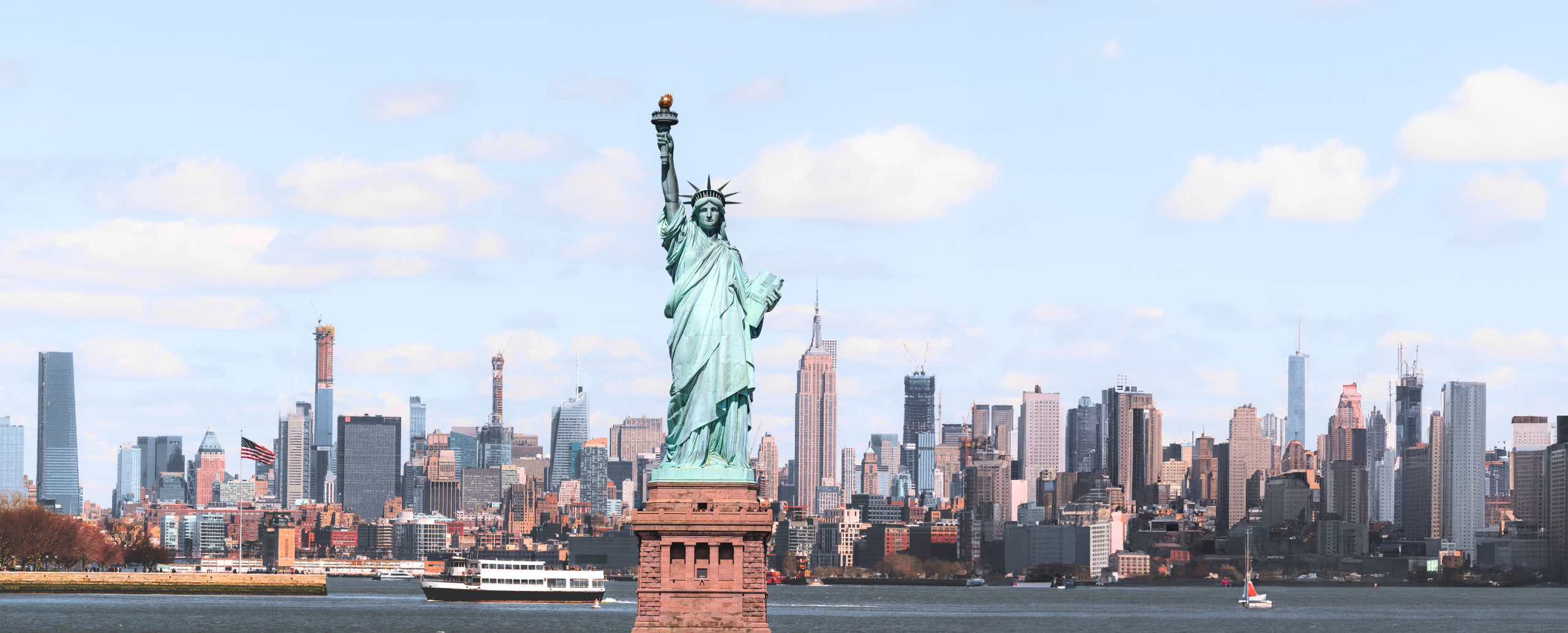 The Statue of Liberty standing tall with city buildings in the background.