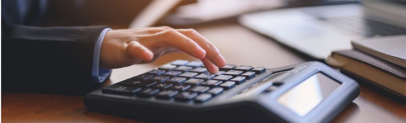 working-at-office-desk-with-calculator-and-laptop-2023-11-27-05-08-58-utc